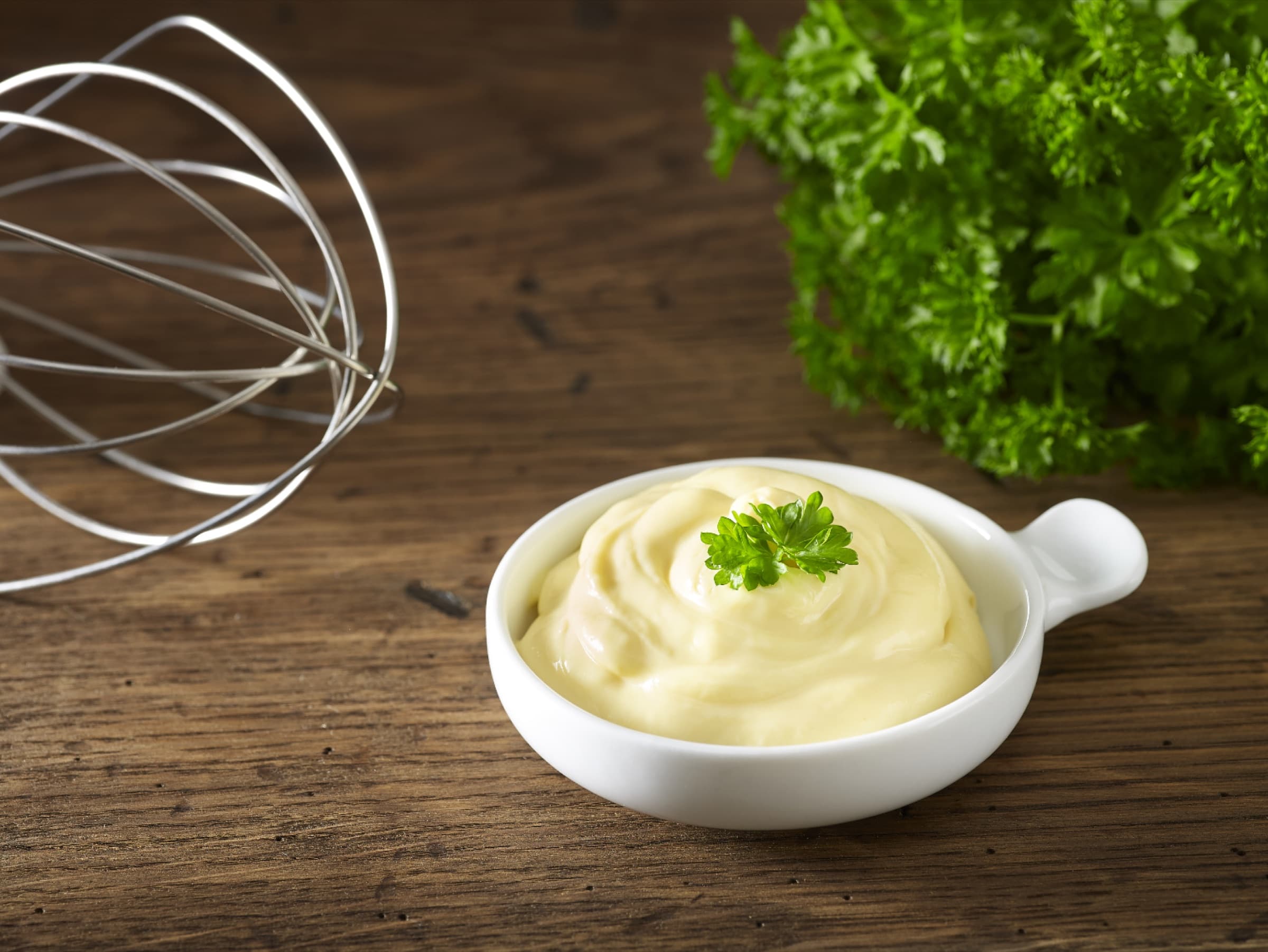 Homemade mayonnaise with a whisk and parsley